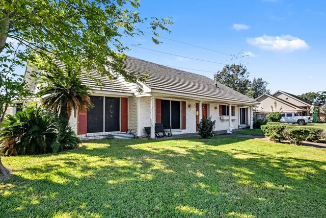 a view of a brick house with a big yard and large trees