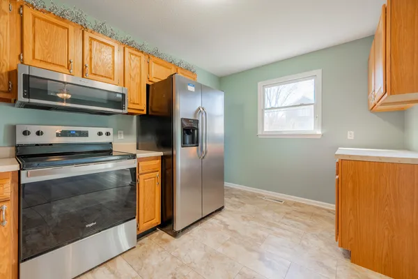 a kitchen with stainless steel appliances granite countertop a refrigerator a stove and a sink with wooden floor