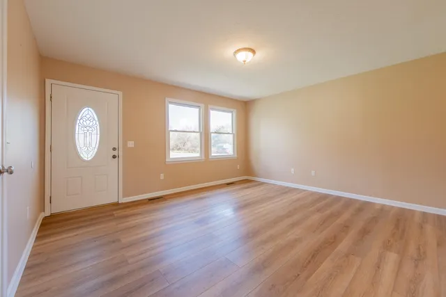 an empty room with wooden floor and windows