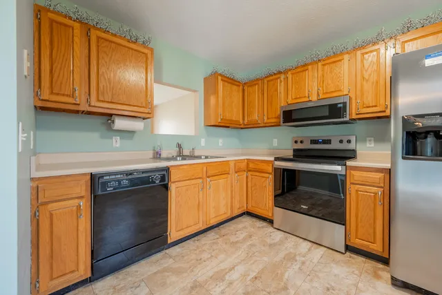 a kitchen with granite countertop wooden cabinets stainless steel appliances and a window
