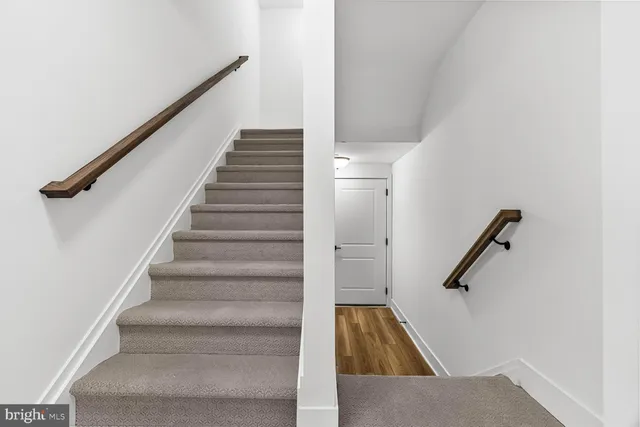 a view of staircase with wooden floor and white walls