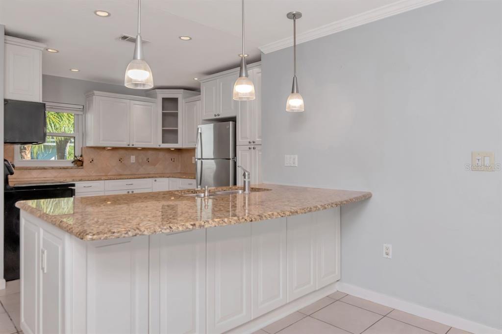 2650 Countryside Boulevard, Unit F303 Clearwater, FL 33761 - Photo 16 of 39 a kitchen with kitchen island a counter top a stove a sink and a refrigerator