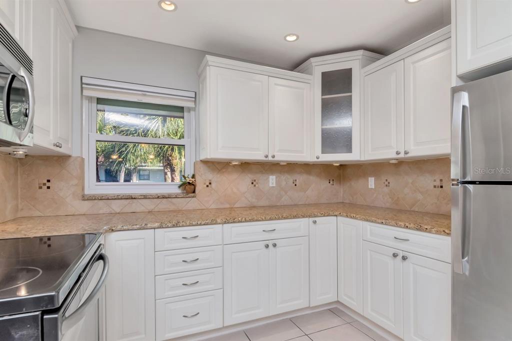2650 Countryside Boulevard, Unit F303 Clearwater, FL 33761 - Photo 19 of 39 a kitchen with granite countertop white cabinets and window