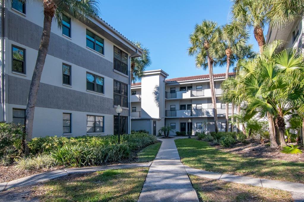 2650 Countryside Boulevard, Unit F303 Clearwater, FL 33761 - Photo 2 of 39 a front view of a residential apartment building with a yard and large trees