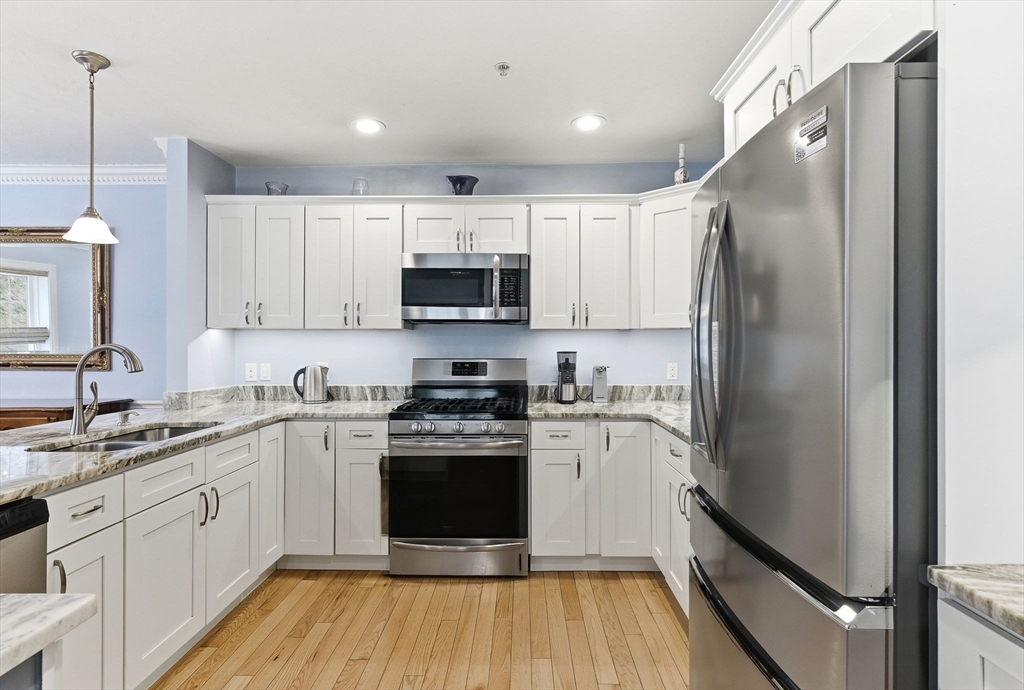 6 Trail Ridge Way, Unit D Harvard, MA 01451 - Photo 3 of 28 a kitchen with stainless steel appliances granite countertop a refrigerator a sink dishwasher a stove and white cabinets with wooden floor