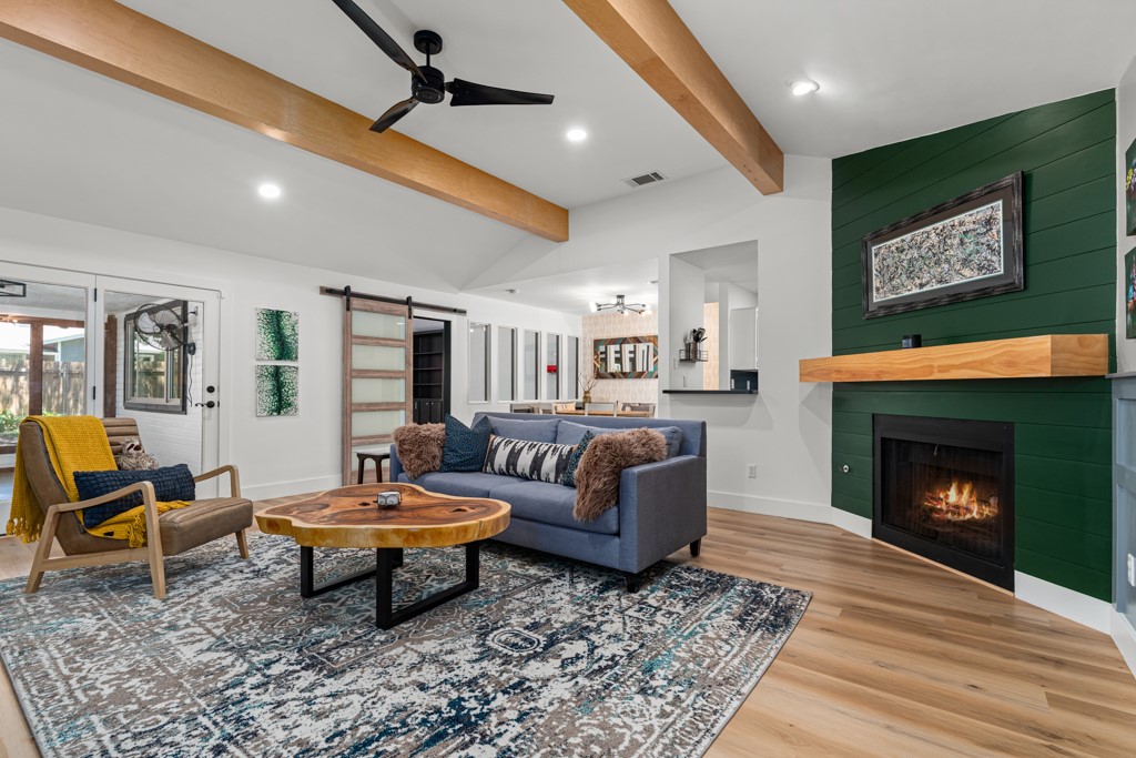 Vibrant emerald green accent wall elevates a cozy living area with a fireplace and wood beams.