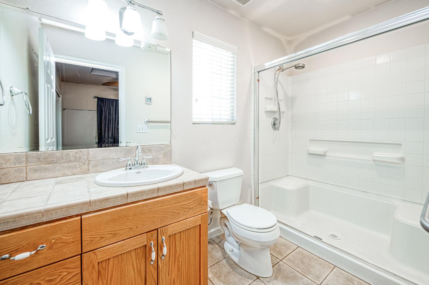 5578 Perrin Road Clovis, CA 93619 - Photo 40 of 62 a bathroom with a granite countertop sink toilet a shower and a mirror