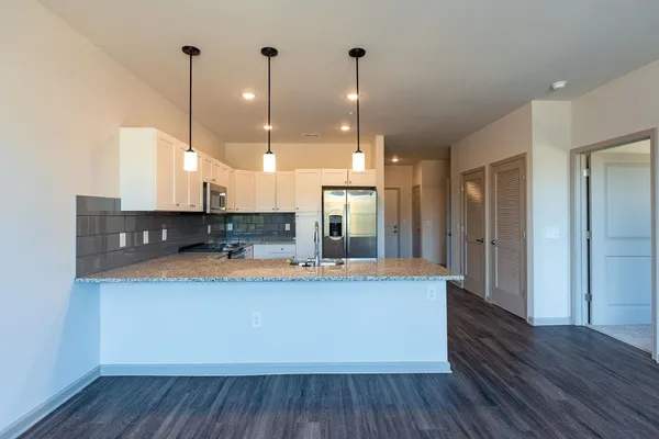 a large kitchen with stainless steel appliances granite countertop a sink a refrigerator and a wooden floor