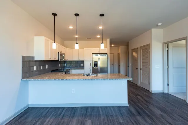 a large kitchen with stainless steel appliances granite countertop a sink a refrigerator and a wooden floor