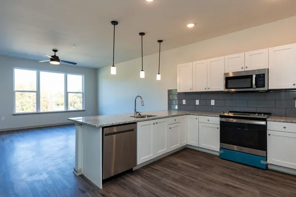 a kitchen with stainless steel appliances granite countertop a sink a stove a kitchen island and wooden floor