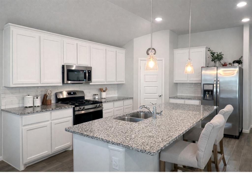 6609 Adderly Road Pilot Point, TX 76258 - Photo 4 of 15 a kitchen with kitchen island granite countertop a sink refrigerator and cabinets