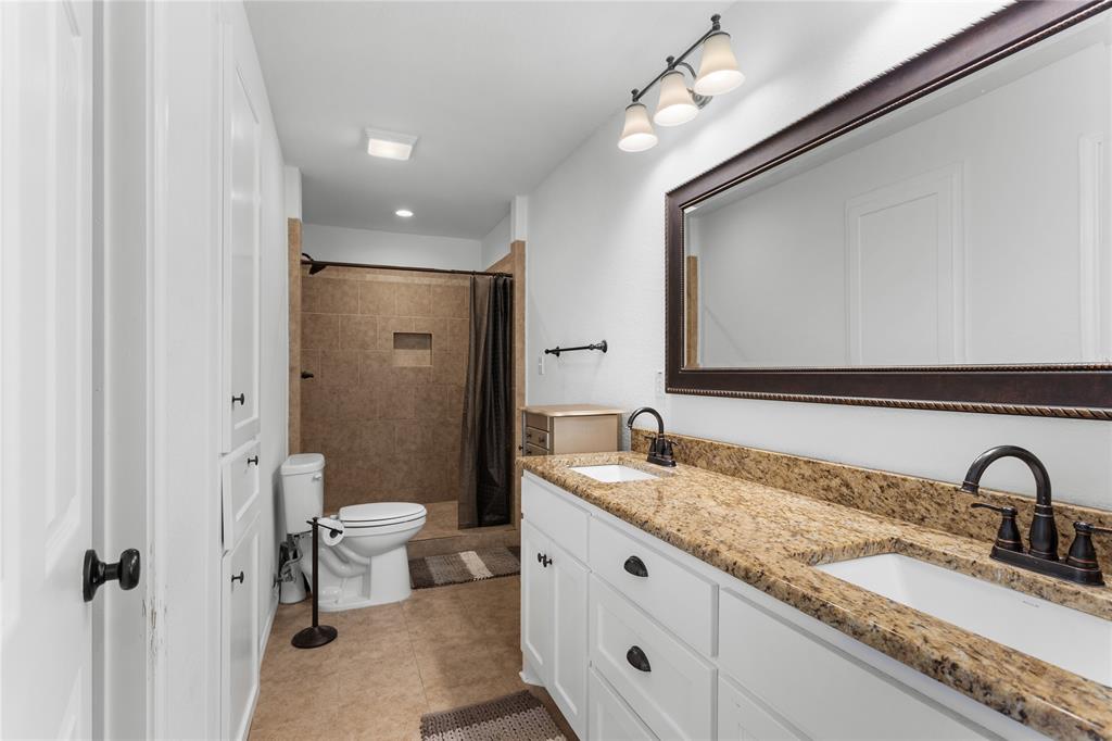 900 Bosque Street Meridian, TX 76665 - Photo 15 of 30 a bathroom with a granite countertop sink a mirror and a shower