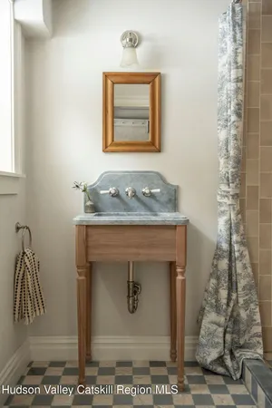 a bathroom with a granite countertop sink a mirror and shower