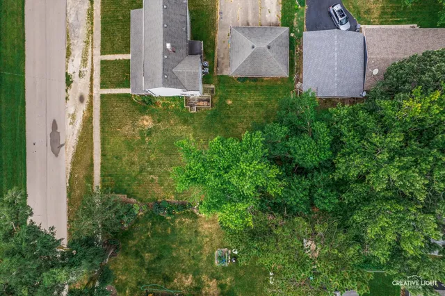 an aerial view of a house with a yard and a large tree