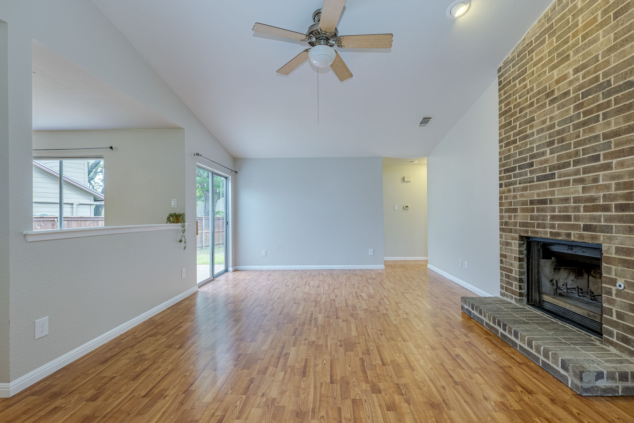 4815 Transit Circle Austin, TX 78727 - Photo 6 of 35 Spacious living area featuring a raised hearth fireplace and vaulted ceiling, with a view toward the hallway and bedrooms.