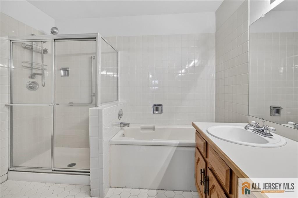 40C Rutland Lane, Unit 40B Monroe Township, NJ 08831 - Photo 25 of 37 a bathroom with a shower sink vanity and mirror