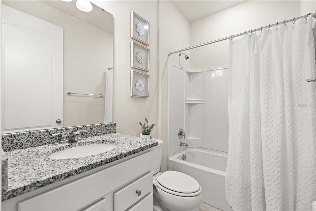 5192 Chickadee Street St. Cloud, FL 34771 - Photo 14 of 35 a bathroom with a granite countertop sink a toilet and shower