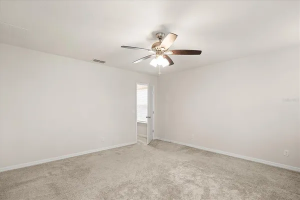 an empty room with fan and windows