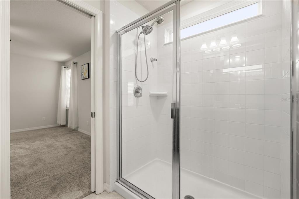 5192 Chickadee Street St. Cloud, FL 34771 - Photo 22 of 35 a bathroom with a glass shower door and a glass door