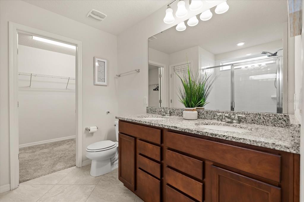 5192 Chickadee Street St. Cloud, FL 34771 - Photo 23 of 35 a bathroom with a granite countertop sink a toilet and mirror