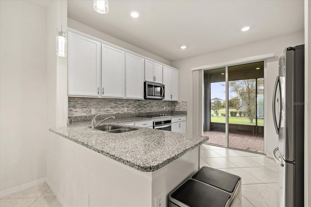 5192 Chickadee Street St. Cloud, FL 34771 - Photo 6 of 35 a kitchen with granite countertop a stove a sink and a microwave