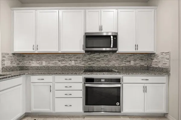 a kitchen with white cabinets and stainless steel appliances