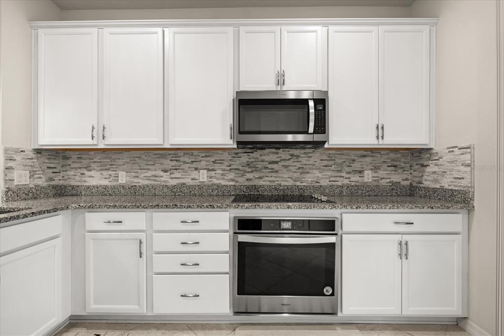 5192 Chickadee Street St. Cloud, FL 34771 - Photo 7 of 35 a kitchen with white cabinets and stainless steel appliances