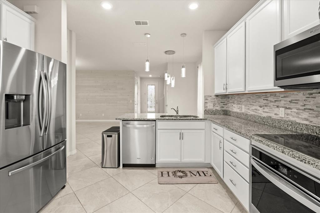 5192 Chickadee Street St. Cloud, FL 34771 - Photo 9 of 35 a kitchen with white cabinets and stainless steel appliances