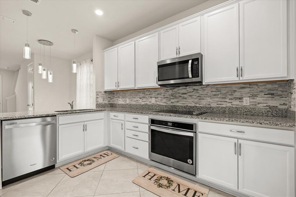 5192 Chickadee Street St. Cloud, FL 34771 - Photo 10 of 35 a kitchen with granite countertop white cabinets stainless steel appliances and a sink