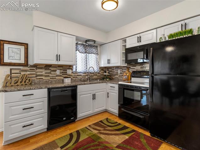 142 Mac Neil Road Pueblo, CO 81001 - Photo 11 of 24 Kitchen featuring black appliances, tasteful backsplash, white cabinetry, and sink