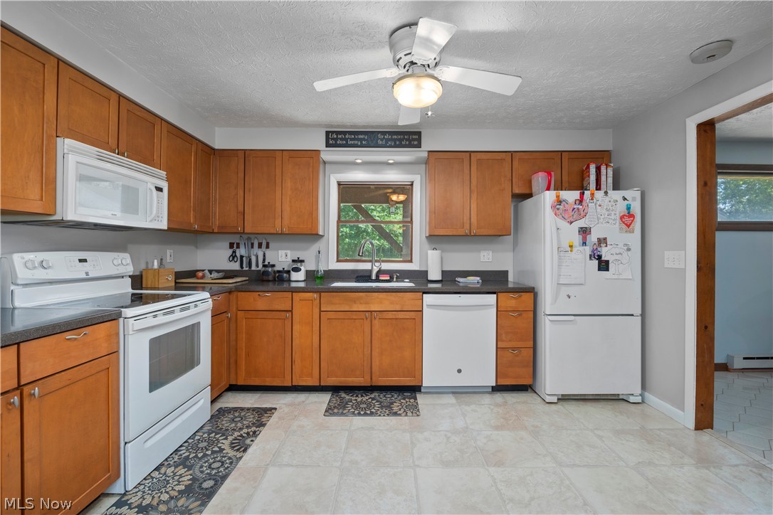 2565 Abbe Road North Sheffield Lake, OH 44054 - Photo 6 of 32 Kitchen featuring white appliances, healthy amount of natural light, brown cabinetry, and a textured ceiling