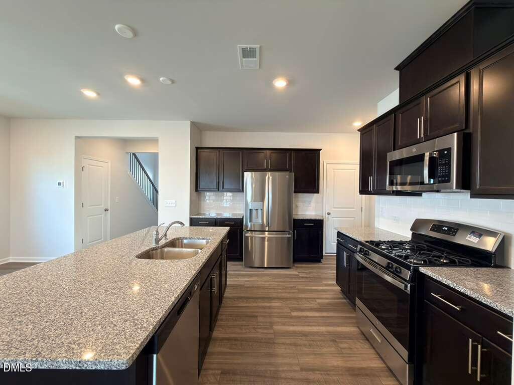 2007 English Saddle Lane Durham, NC 27703 - Photo 11 of 45 a kitchen with stainless steel appliances granite countertop a stove top oven a sink dishwasher a refrigerator and cabinets with wooden floor