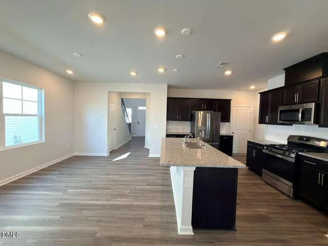 a large kitchen with stainless steel appliances kitchen island granite countertop a large counter top and wooden floors