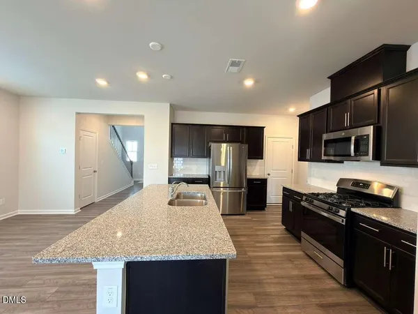 a large kitchen with stainless steel appliances kitchen island granite countertop a stove and a sink