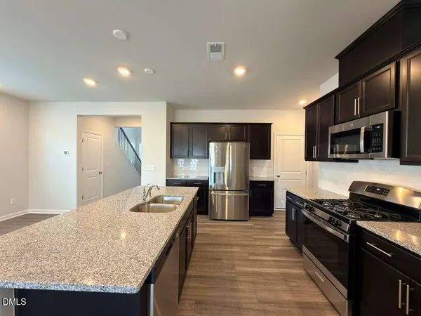 a kitchen with stainless steel appliances granite countertop a stove top oven a sink dishwasher a refrigerator and a microwave