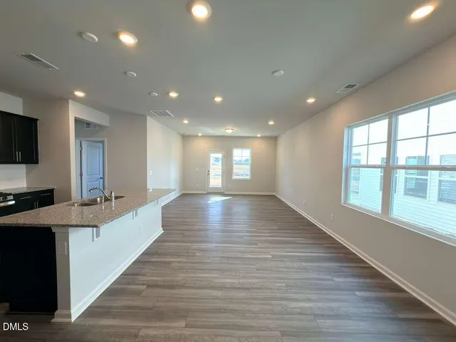 a view of a kitchen with kitchen island a sink wooden floor and a large window