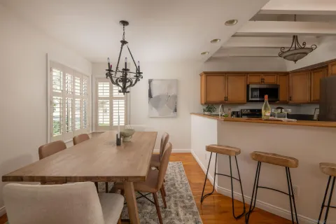 a kitchen with stainless steel appliances granite countertop a dining table chairs and a refrigerator