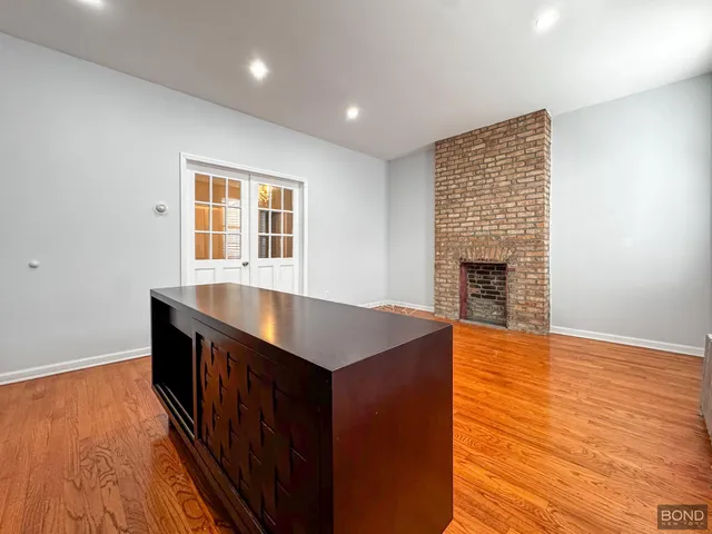 an empty room with wooden floor fireplace and windows
