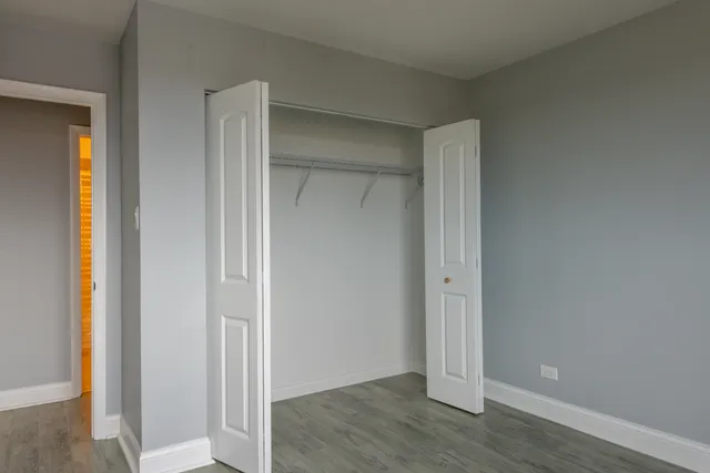 an empty room with wooden floor & closet area