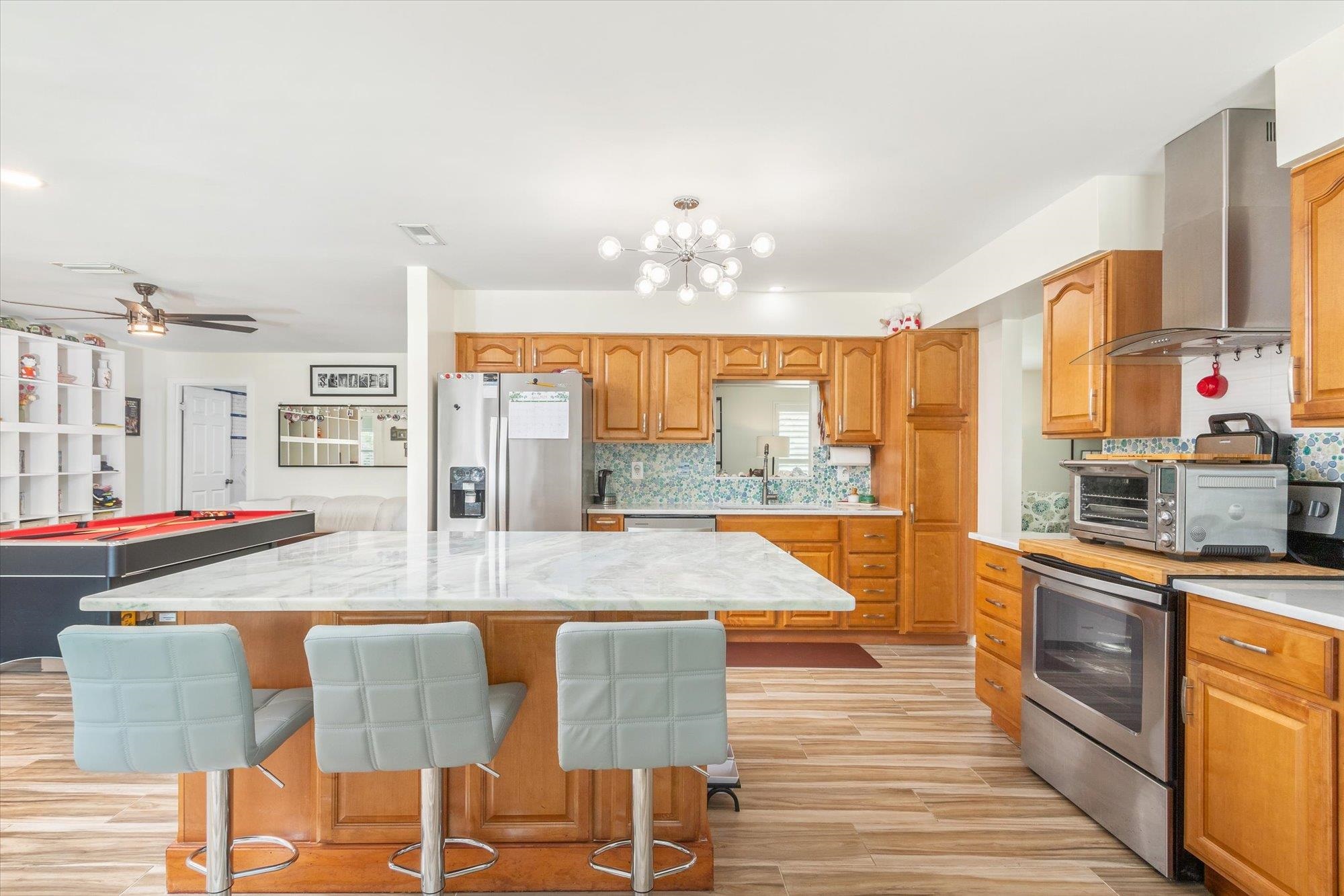 5 Cheyenne Court Palm Coast, FL 32137 - Photo 14 of 58 a dining hall with stainless steel appliances granite countertop a kitchen island a stove a dining table and chairs with wooden floor
