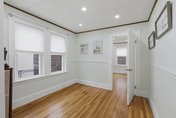 a view of empty room with wooden floor and fan