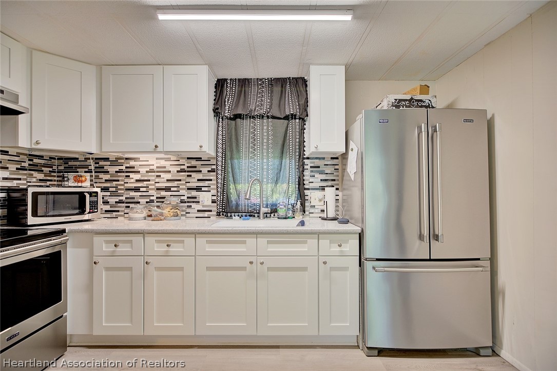 310 Pine Tree Lane Sebring, FL 33872 - Photo 3 of 28 a kitchen with white cabinets and stainless steel appliances