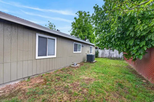 a backyard of a house with wooden fence and large trees