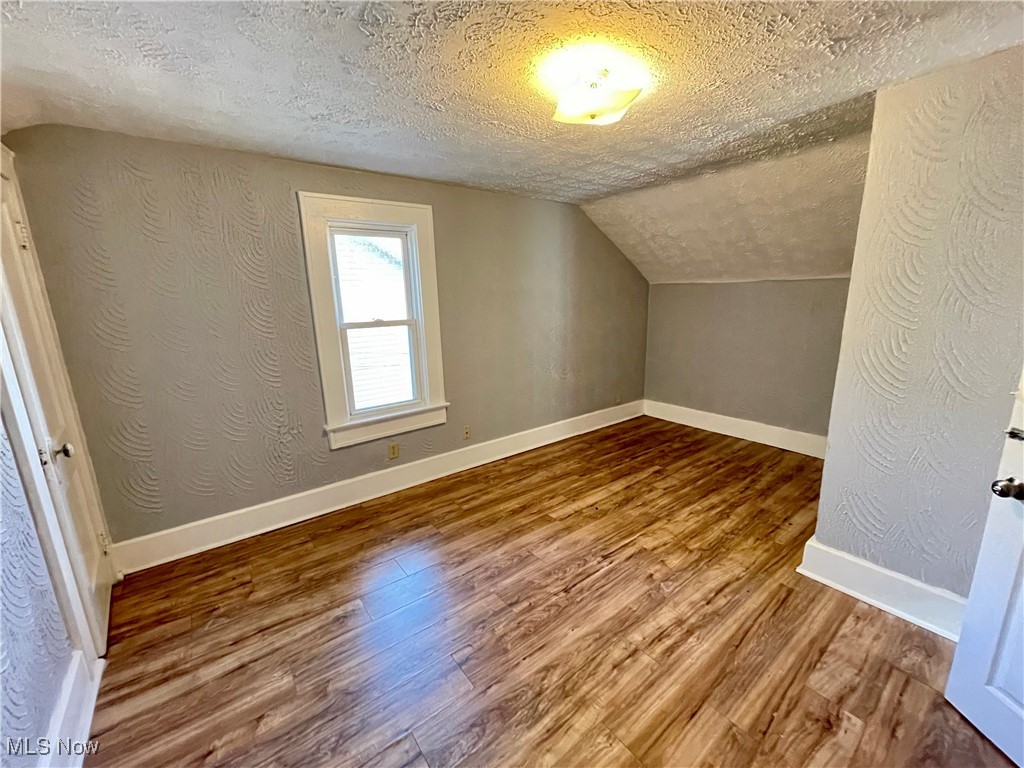 1072 Pitkin Avenue Akron, OH 44310 - Photo 8 of 13 Bonus room with a textured ceiling, wood finished floors, and vaulted ceiling