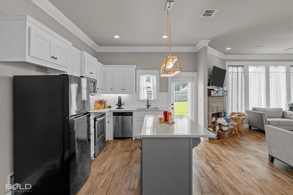 6896 Bethany Reed Circle Blanchard, LA 71107 - Photo 23 of 37 Open-concept kitchen featuring white shaker cabinetry, stainless steel appliances, and wood-finish flooring