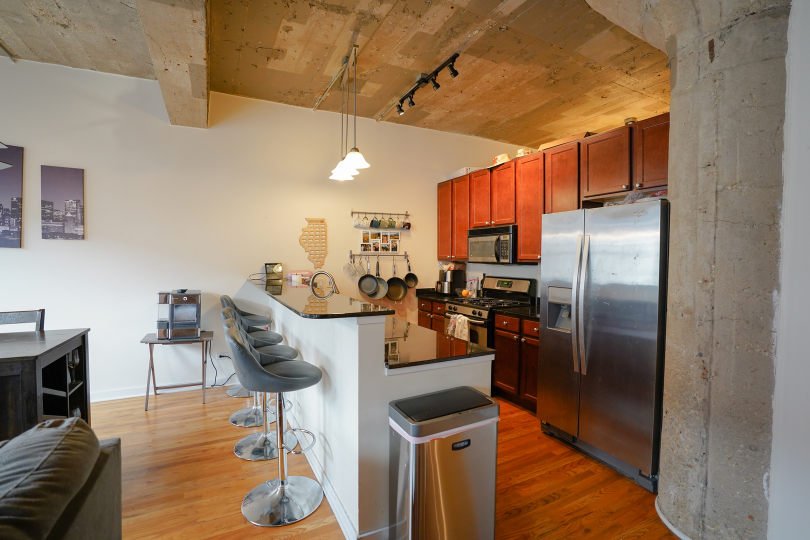 1069 West 14th Place, Unit 303 Chicago, IL 60608 - Photo 3 of 26 a kitchen with stainless steel appliances granite countertop a refrigerator a stove a sink a dining table and chairs with wooden floor
