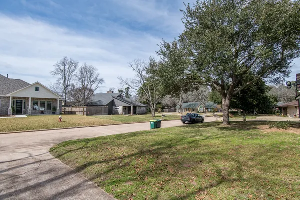 a view of a house with a big yard and large trees