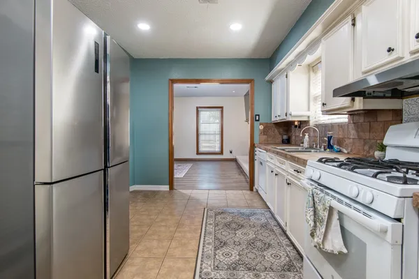 a large kitchen with stainless steel appliances granite countertop a stove and a refrigerator