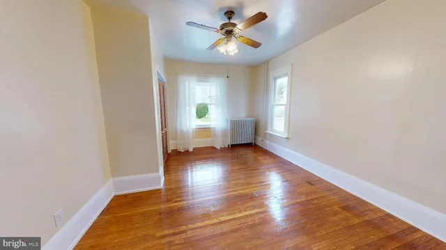 a view of an empty room with window and wooden floor