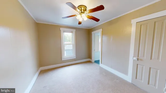 a view of an empty room with window and a chandelier fan